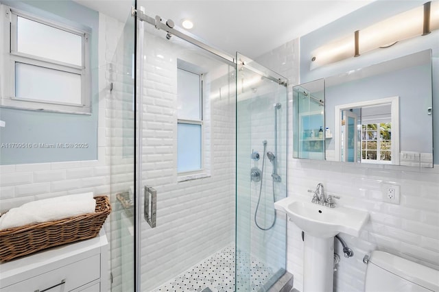 bathroom featuring toilet, a shower with shower door, tile walls, and tasteful backsplash