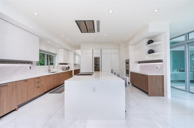 kitchen with white cabinets, a spacious island, sink, tasteful backsplash, and stainless steel appliances