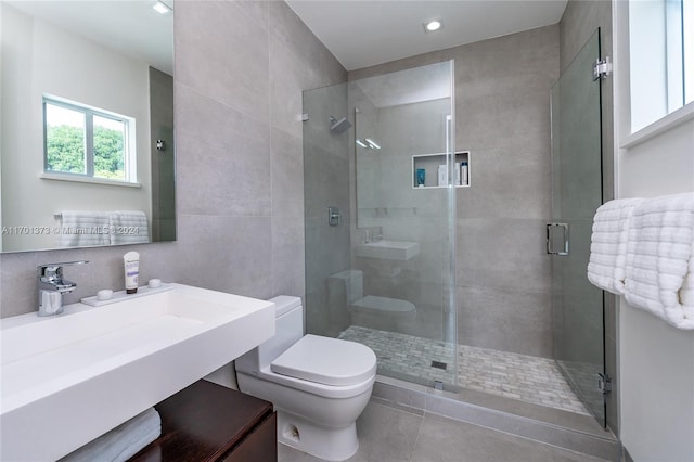 bathroom featuring tile patterned flooring, toilet, a shower with door, and sink