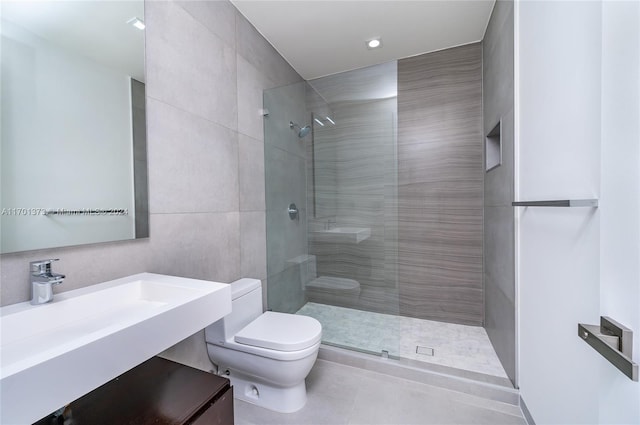 bathroom with a tile shower, toilet, tile patterned floors, and sink