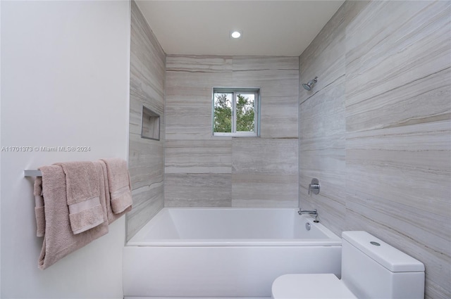 bathroom featuring toilet and tiled shower / bath