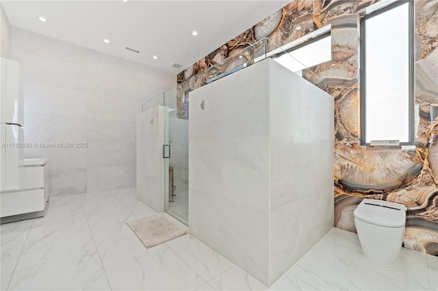 bathroom featuring a shower with door, vanity, tile walls, and toilet