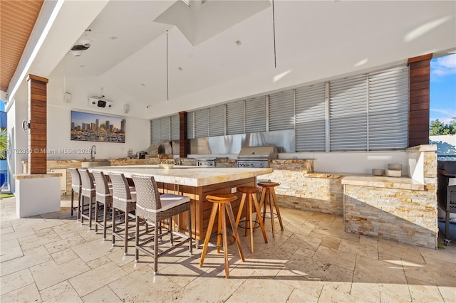 interior space featuring a kitchen bar, high vaulted ceiling, a spacious island, and sink