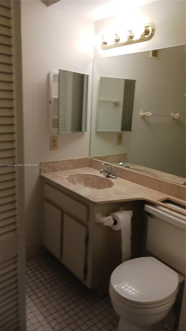 bathroom with toilet, vanity, and tile patterned floors