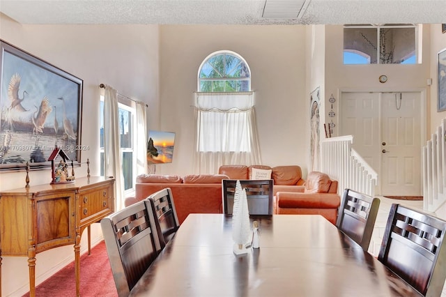 carpeted dining space with a towering ceiling and a textured ceiling