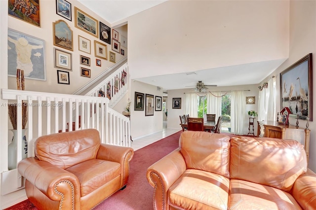 carpeted living room with ceiling fan and a high ceiling