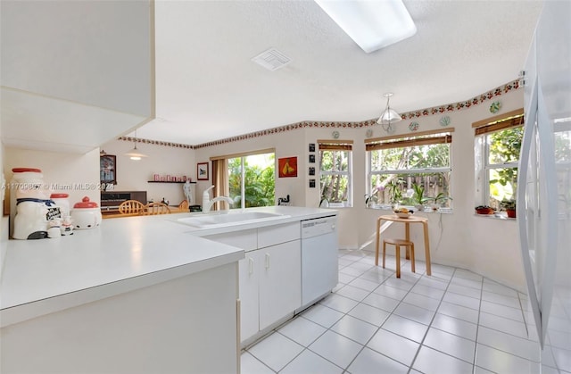 kitchen featuring dishwasher, sink, kitchen peninsula, light tile patterned floors, and white cabinetry