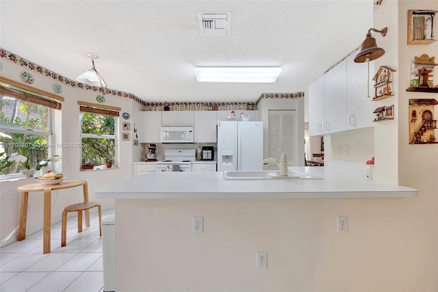 kitchen featuring white appliances, white cabinets, sink, light tile patterned floors, and kitchen peninsula