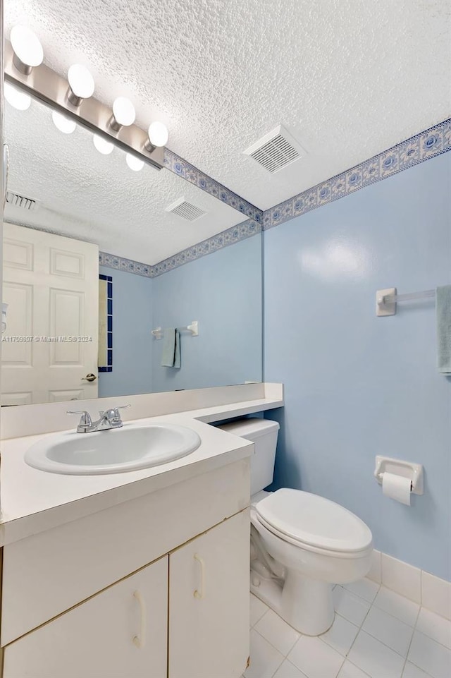 bathroom with vanity, a textured ceiling, toilet, and tile patterned flooring