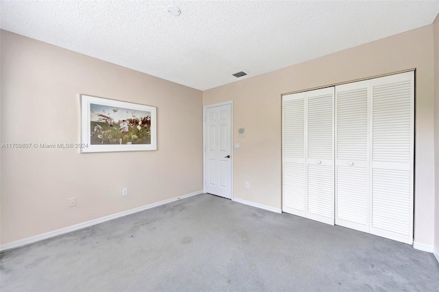 unfurnished bedroom with carpet flooring, a textured ceiling, and a closet