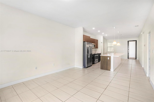 kitchen featuring a kitchen island with sink, sink, decorative light fixtures, light tile patterned flooring, and stainless steel appliances