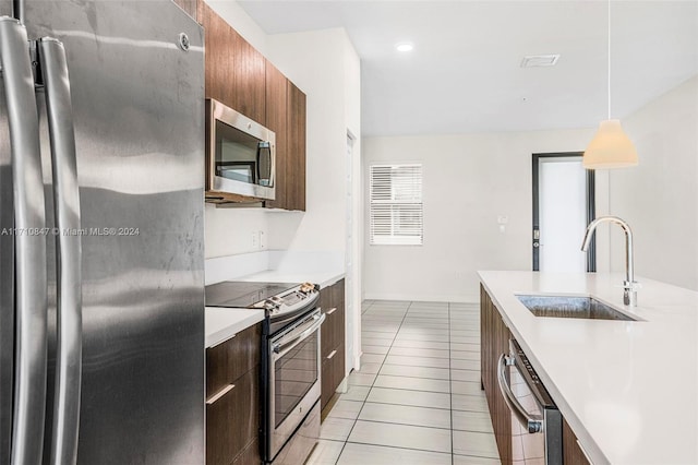 kitchen with sink, light tile patterned floors, decorative light fixtures, and appliances with stainless steel finishes