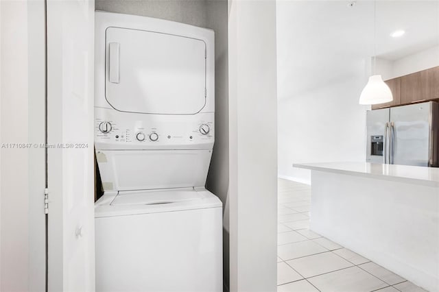 washroom with stacked washer / drying machine and light tile patterned floors