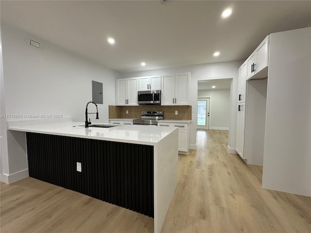 kitchen with white cabinetry, sink, kitchen peninsula, light hardwood / wood-style floors, and appliances with stainless steel finishes