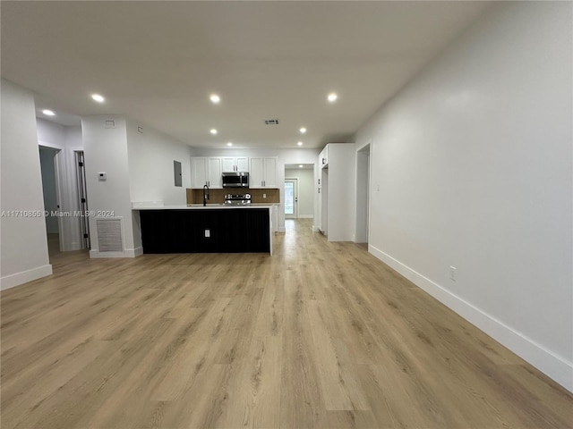 kitchen with sink, white cabinetry, light hardwood / wood-style floors, kitchen peninsula, and stainless steel appliances