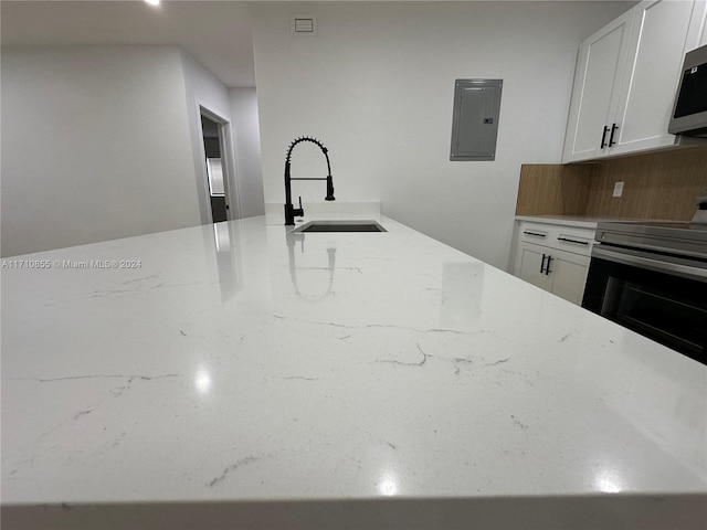 kitchen featuring electric panel, white cabinets, sink, light stone countertops, and electric range oven