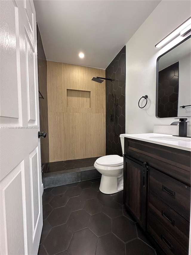 bathroom with tiled shower, vanity, tile patterned floors, and toilet