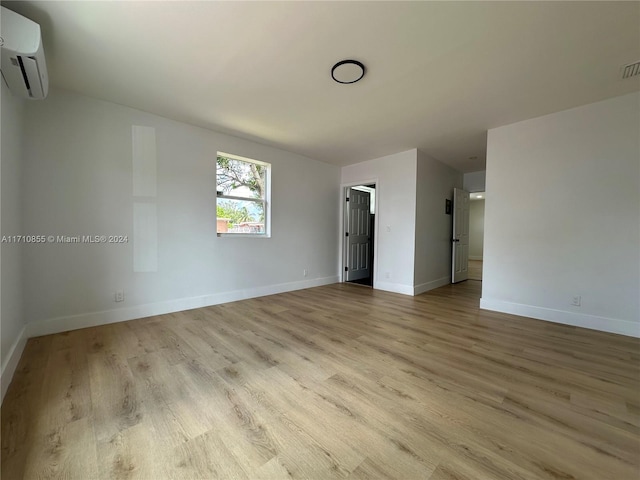 unfurnished room with light wood-type flooring and a wall mounted AC