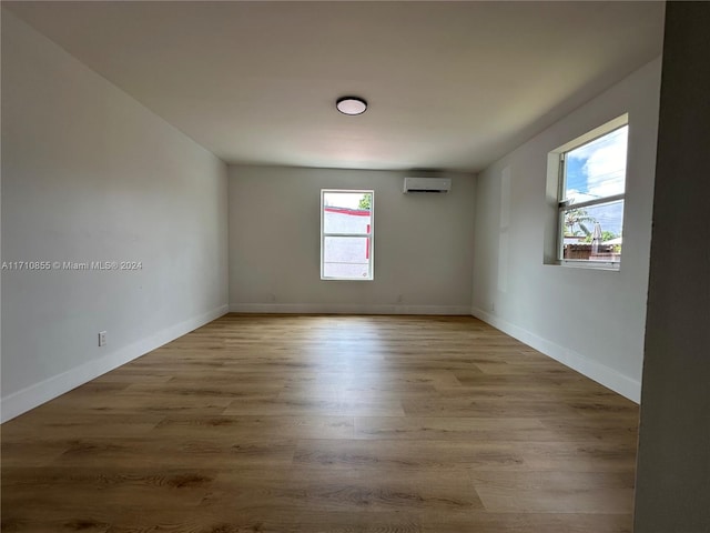 spare room featuring a healthy amount of sunlight, light hardwood / wood-style floors, and a wall unit AC