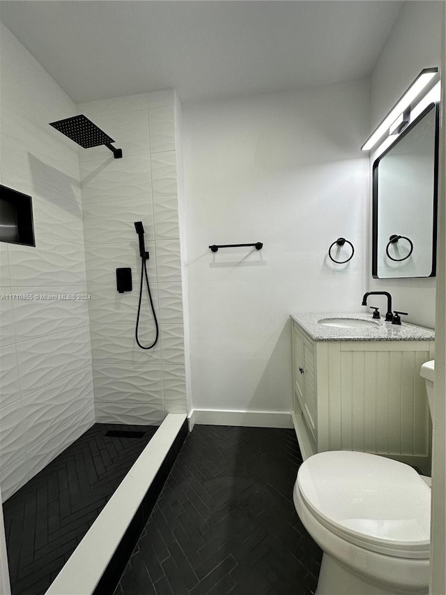 bathroom featuring tiled shower, vanity, and toilet