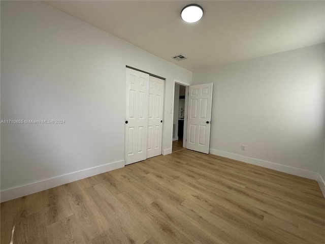 unfurnished bedroom with light wood-type flooring and a closet