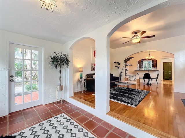 interior space featuring a textured ceiling, ceiling fan with notable chandelier, and dark tile patterned floors