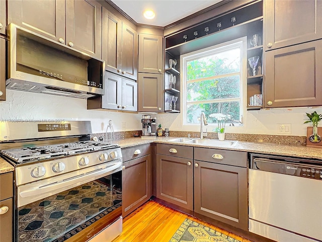 kitchen with light stone countertops, sink, appliances with stainless steel finishes, and light hardwood / wood-style flooring