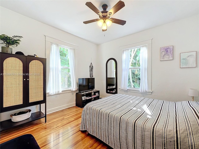 bedroom with ceiling fan, wood-type flooring, and multiple windows