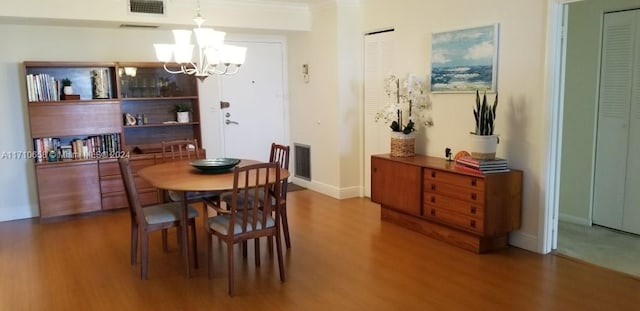 dining room featuring hardwood / wood-style floors, ornamental molding, and an inviting chandelier