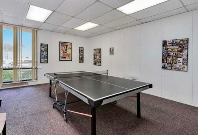 game room featuring dark colored carpet and a drop ceiling