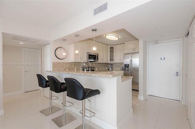 kitchen featuring kitchen peninsula, pendant lighting, stainless steel appliances, and light tile patterned floors