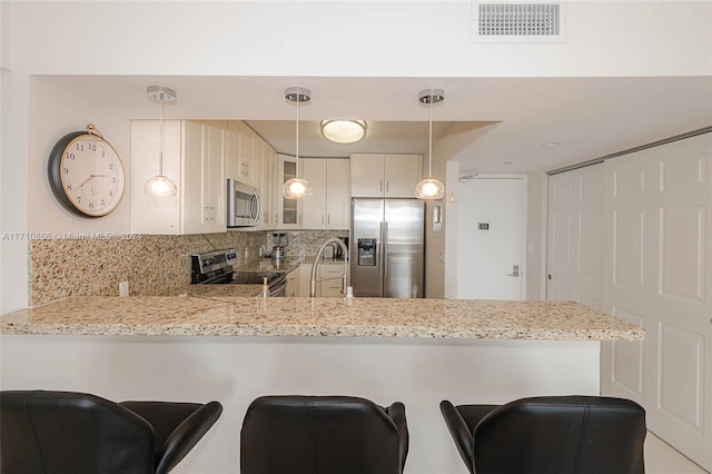 kitchen with white cabinets, a kitchen breakfast bar, kitchen peninsula, and stainless steel appliances