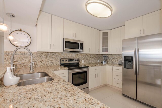 kitchen featuring pendant lighting, sink, appliances with stainless steel finishes, light stone counters, and white cabinetry