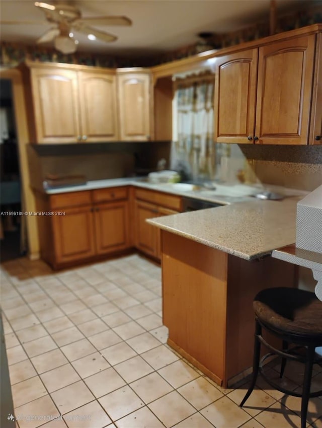 kitchen with kitchen peninsula, light tile patterned floors, and ceiling fan