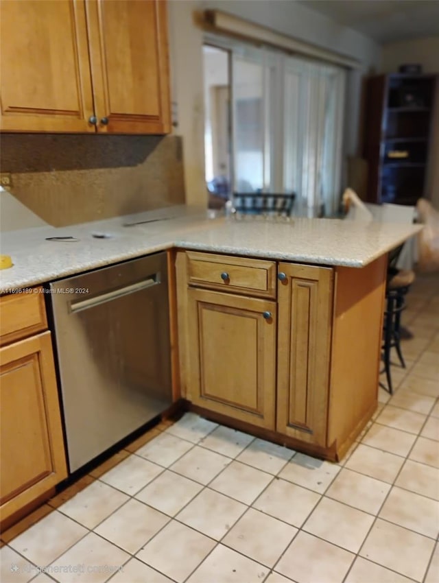 kitchen featuring dishwasher, a breakfast bar, kitchen peninsula, and light tile patterned flooring