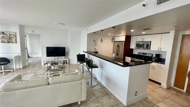 kitchen featuring a breakfast bar, appliances with stainless steel finishes, white cabinetry, and hanging light fixtures