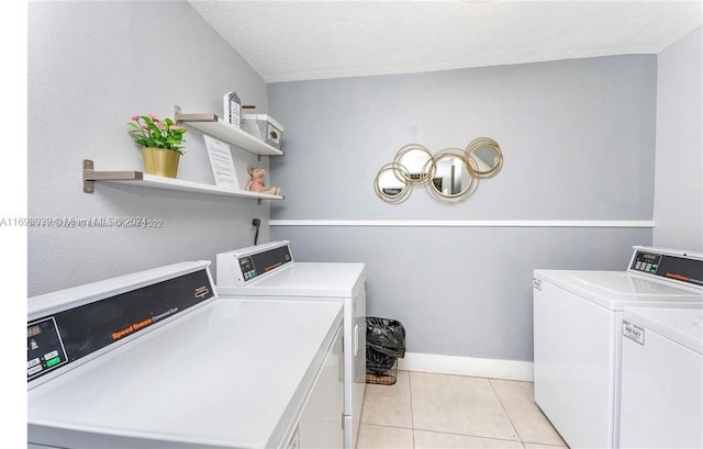 laundry area featuring a textured ceiling, separate washer and dryer, and light tile patterned flooring