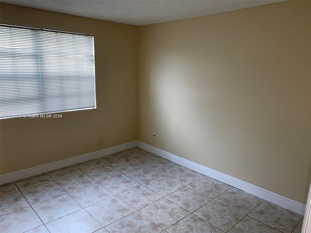 unfurnished room with light tile patterned floors and a textured ceiling