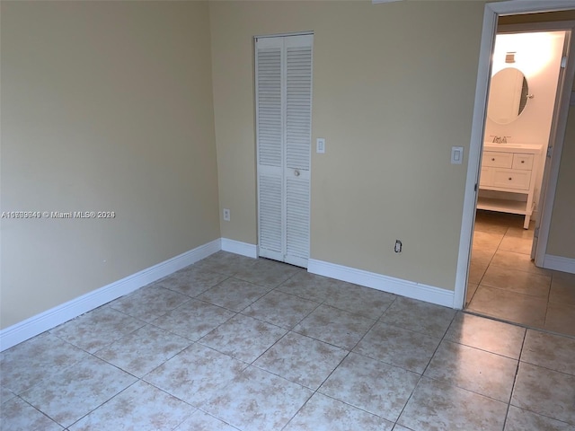 unfurnished bedroom with light tile patterned floors, sink, and a closet