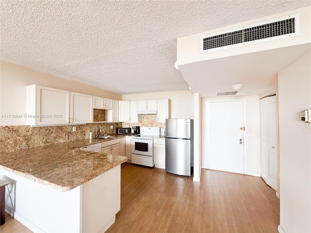 kitchen featuring kitchen peninsula, stainless steel fridge, sink, hardwood / wood-style flooring, and white stove