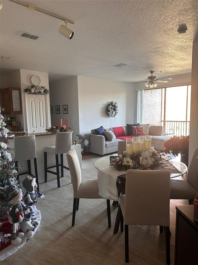 dining space with visible vents, a textured ceiling, and a ceiling fan