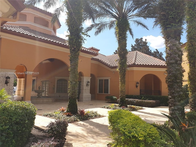 rear view of property with a tiled roof and stucco siding