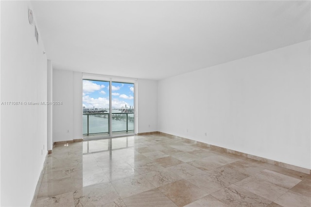 spare room with a water view and floor to ceiling windows