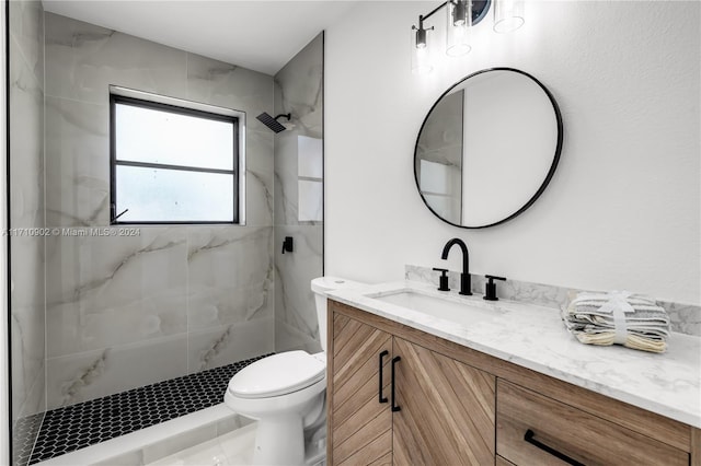 bathroom with vanity, toilet, and a tile shower