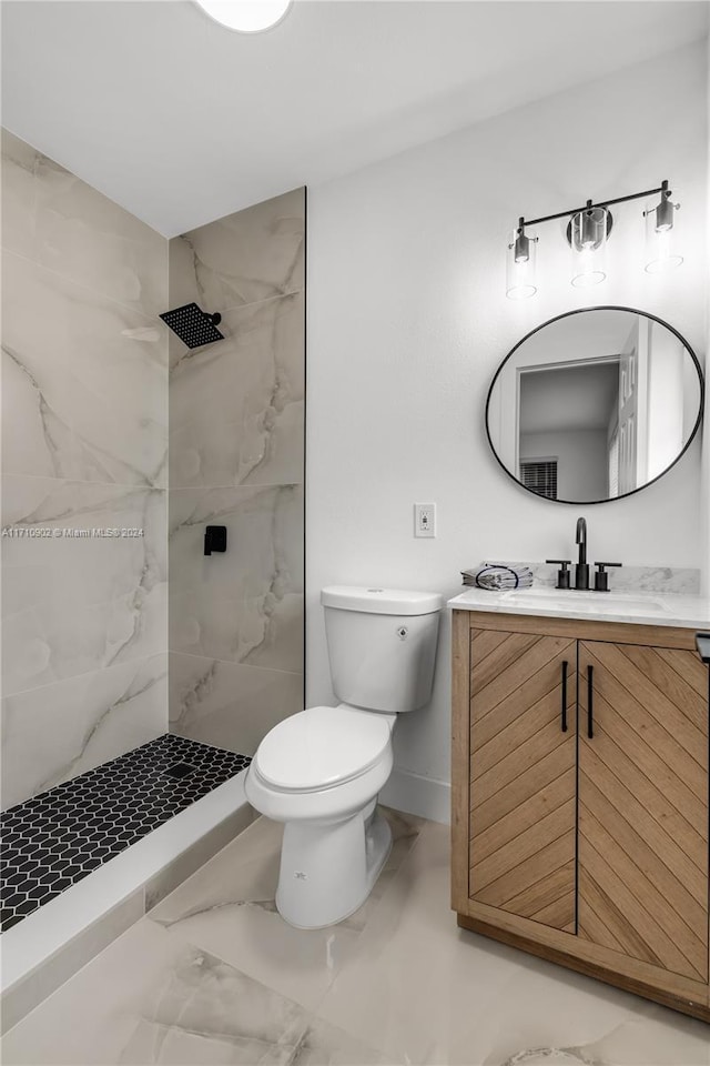 bathroom featuring vanity, toilet, and tiled shower