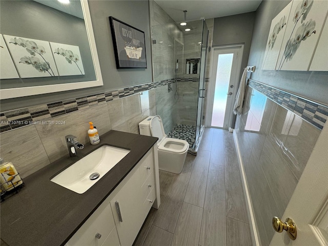 bathroom featuring wood-type flooring, an enclosed shower, toilet, vanity, and tile walls