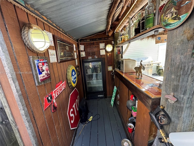 bar featuring wooden walls, hardwood / wood-style flooring, tile counters, and lofted ceiling