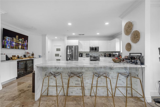 kitchen with kitchen peninsula, appliances with stainless steel finishes, a breakfast bar, and white cabinets