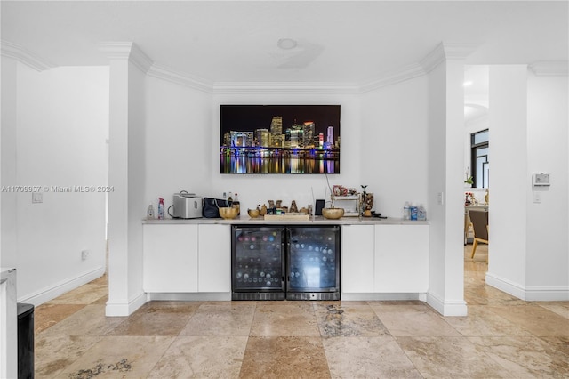 bar with wine cooler, white cabinetry, and ornamental molding