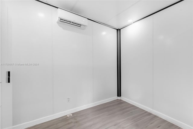 spare room with an AC wall unit and light hardwood / wood-style flooring